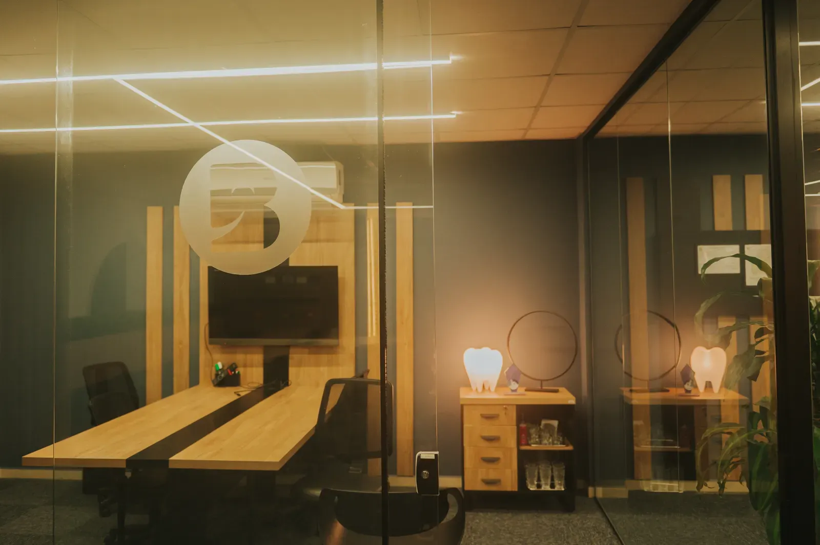 Sala de reunião com paredes de vidro e o logotipo da escola